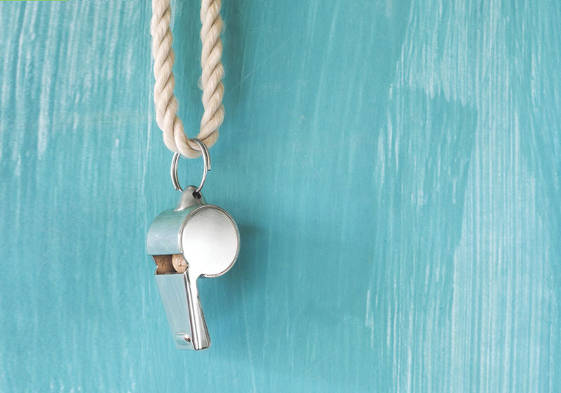 silver whistle hanging from a rope on blue painted background