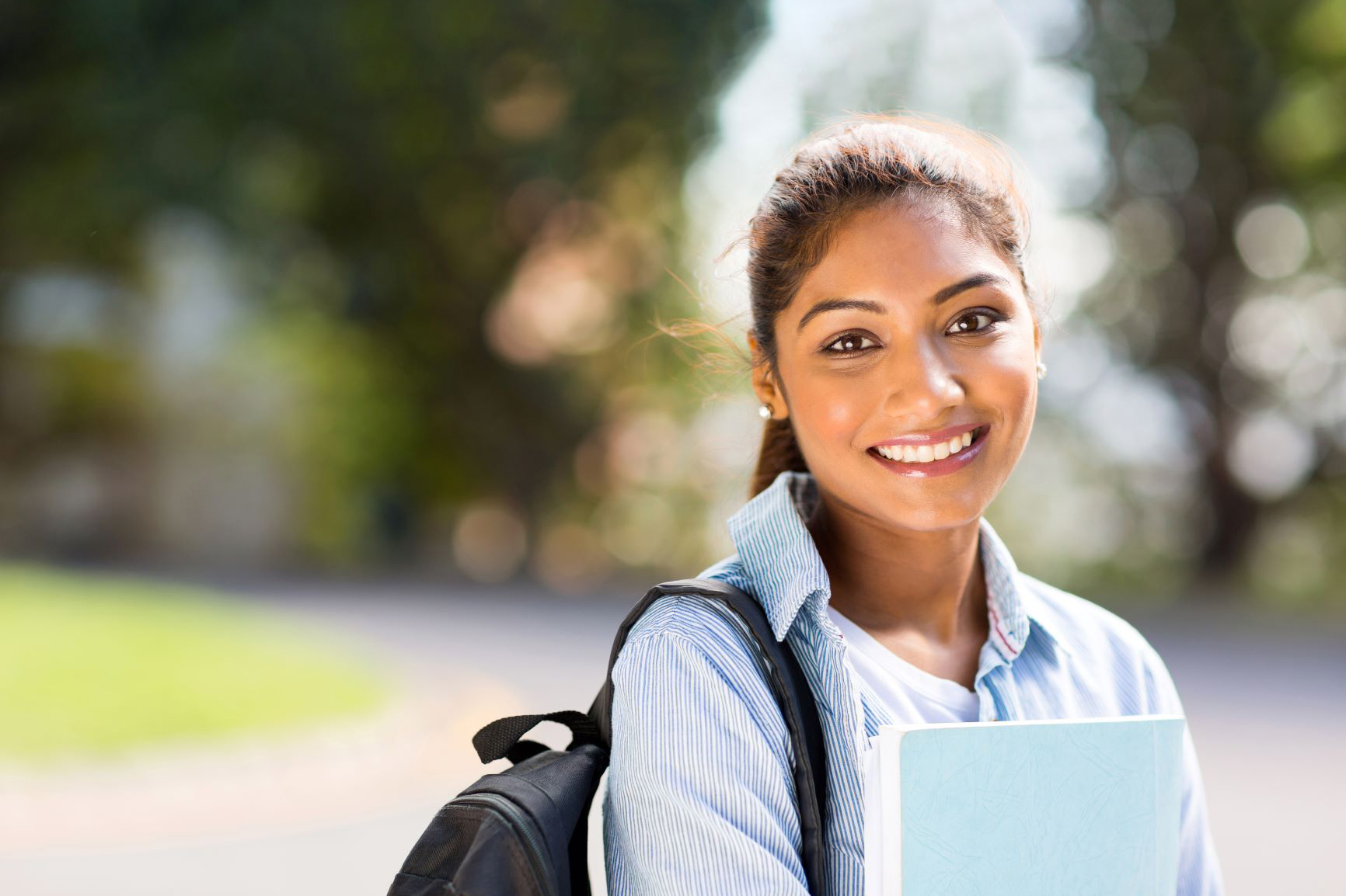 Women with backpack and notebook on a school campus smiling at camera