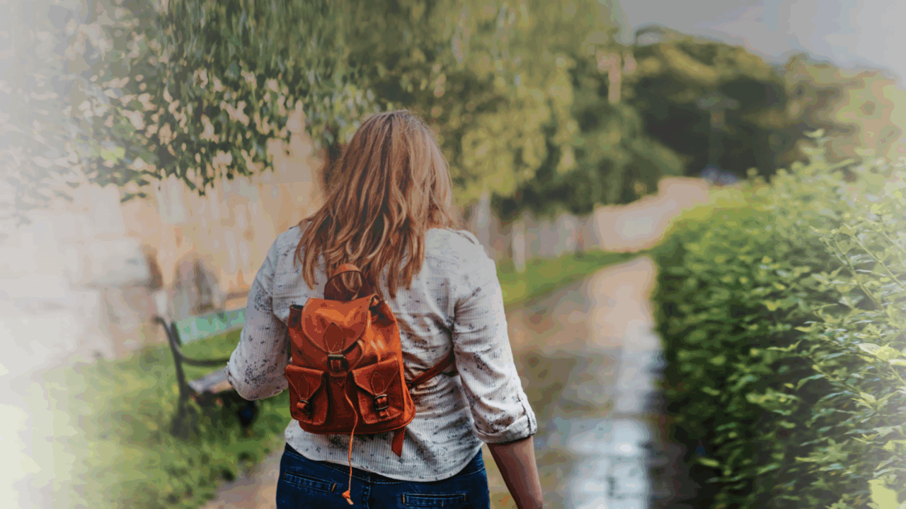 Woman walking down path with backpack