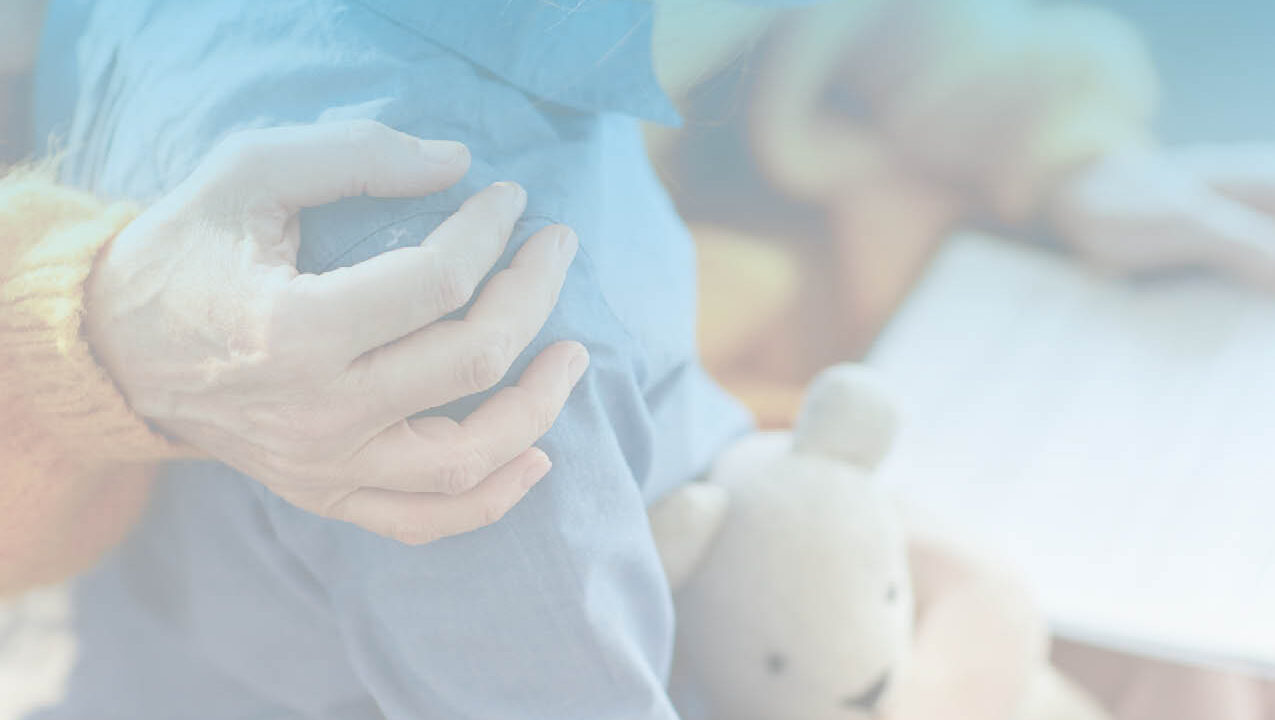 Hand on shoulder of child holding teddy