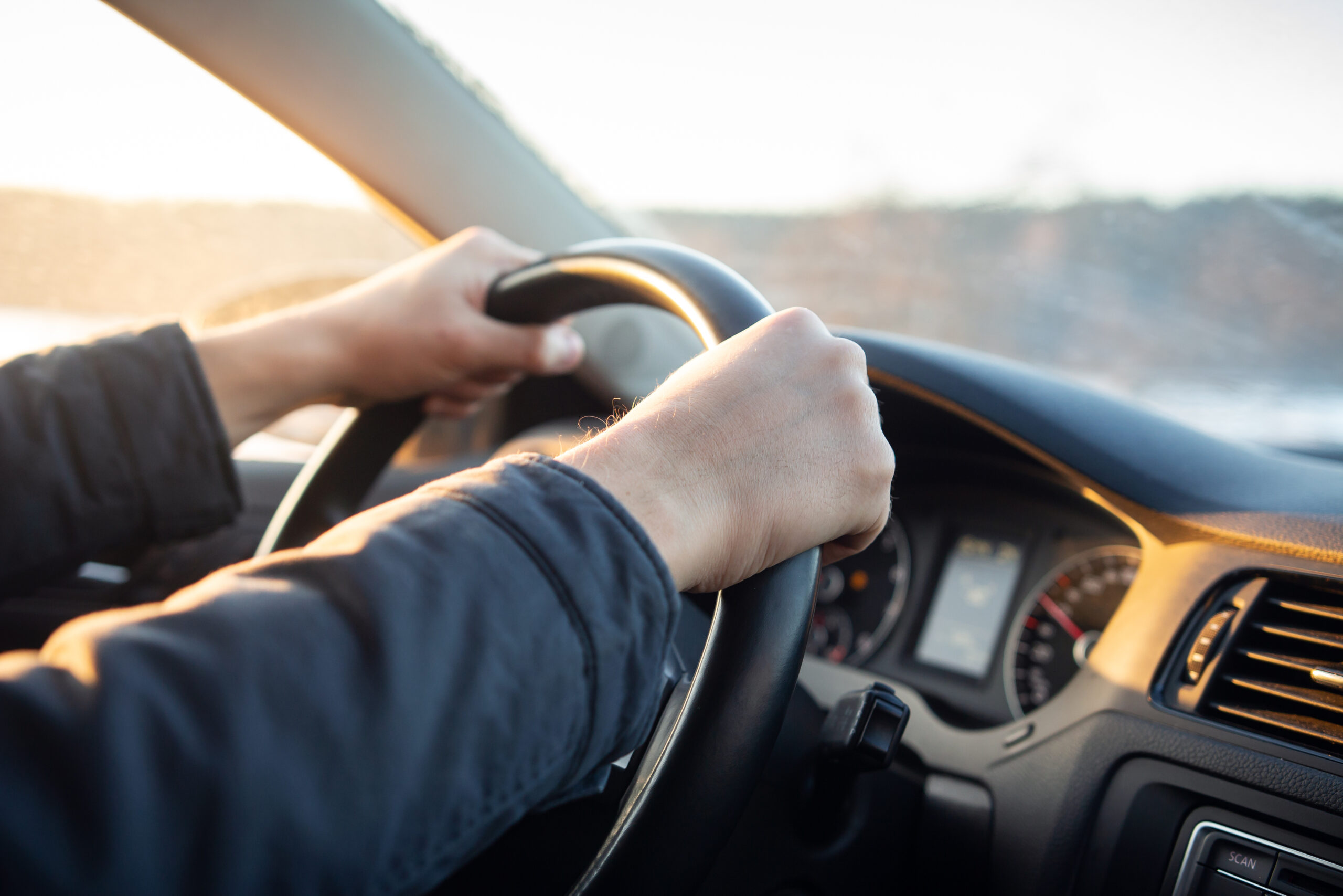 Close-up of driver's hand on steering wheel of car in cabin