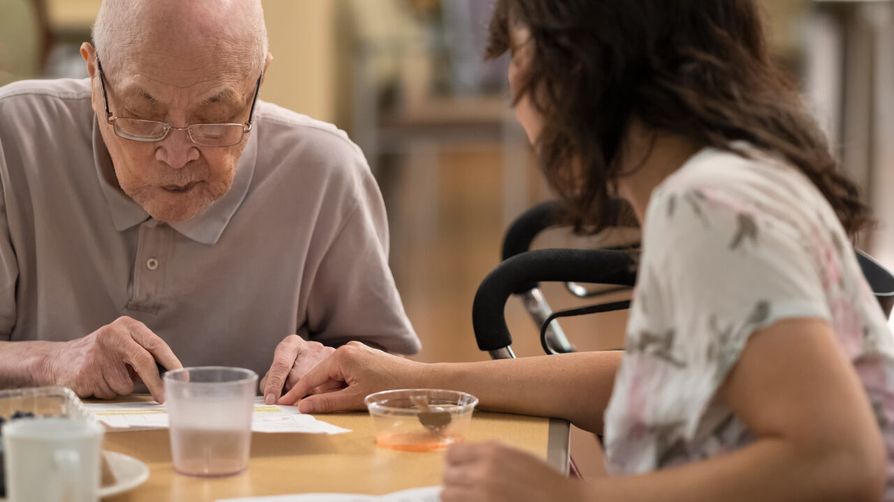 Senior Asian man and mature Asian woman reviewing contract with mobility walker in background. Vancouver, British Columbia, Canada.