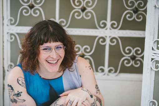 trans woman smiling at the entrance of her house