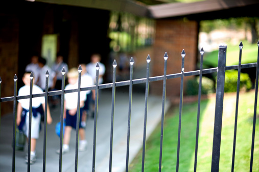Small children leaving school. Focus of fence, very shallow